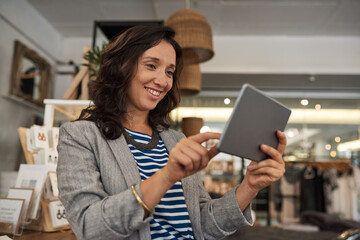 Fototapeta premium Smiling Asian woman working on a tablet in her shop