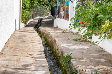 Agua corriendo por acequia dentro de uno de los pueblos blanco de la serranía de ronda.