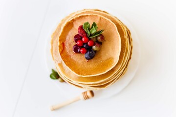 pancakes with berries stand on the white table