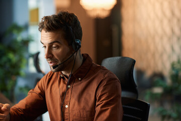 Businessman talking on a headset while working late