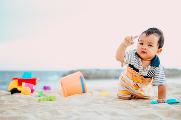 Baby boy playing with beach toys with his mother on tropical beach.Summer family vacation