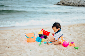 Baby boy playing with beach toys with his mother on tropical beach.Summer family vacation