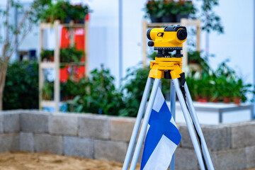 The flag of Finland is attached to theodolite. Construction of cottages in Finland. Cartographic...