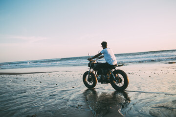 Fototapeta premium Male motorcyclist riding bike on seashore