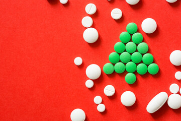 Christmas tree made of green pills and white tablet on red background. new year's card concept for medical field. mockup with with copy space
