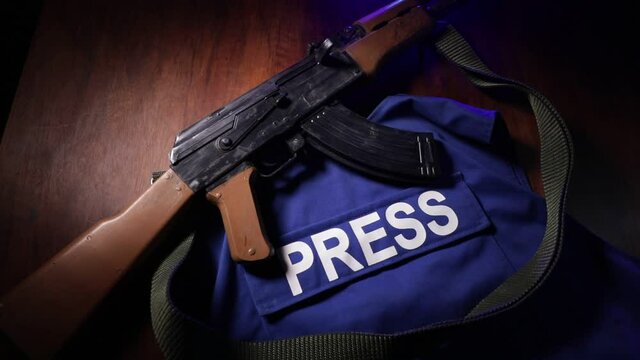 Media Journalism at risk concept. Blue journalist (press) vest in dark with backlight and fog. Weapon on journalist vest. Selective focus