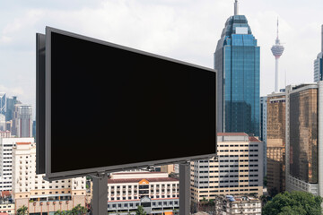 Blank black road billboard with Kuala Lumpur cityscape background at day time. Street advertising poster, mock up, 3D rendering. Side view. The concept of marketing communication.