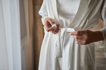 girl ties  belt on her robe standing near window,woman getting ready before wedding ceremony