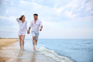 Happy couple having romantic walk on beach. Space for text