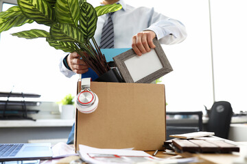 Man business clothes puts things into box at office