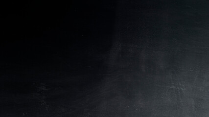 Blackboard with white chalk smeared on it. Empty black chalkboard. School board background with traces of chalk.