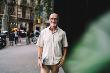 Happy aged man with tablet standing on street