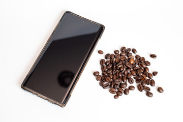 coffee beans and black screen mobile phone on white background