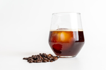 A glass of coffee and coffee beans on white background