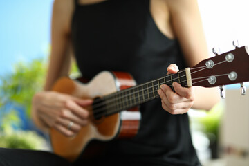 Closeup of a woman learning to play ukulele