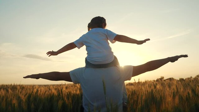 happy family silhouette teamwork concept slow motion video. daughter little girl sitting on his father man neck depicts a flight of an airplane playing a pilot. parent dad and child kid daughter