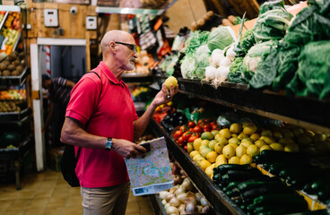 Concentrated senior vegetarian choosing lemon in market