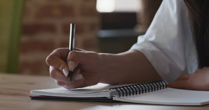 Close up of female hands writing essay in notebook