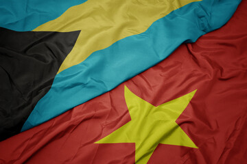 waving colorful flag of vietnam and national flag of bahamas.