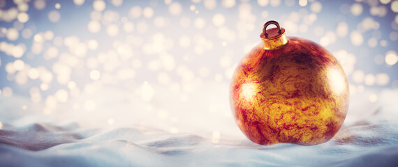 Christmas golden ball on snow. Glitter lights