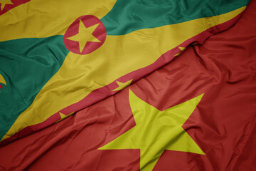 waving colorful flag of vietnam and national flag of grenada.