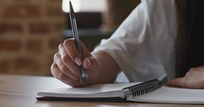 Woman knocking on notebook with pen, thinking process