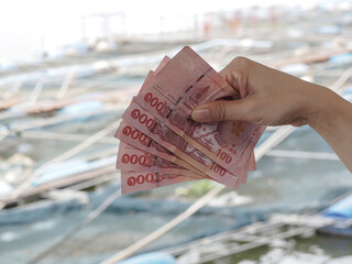 woman's hand holding a fan of one hundred Thai bank note five bills, business concept