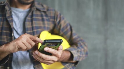 construction worker hands using smartphone on cement wall background with copy space