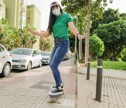 Beautiful asian woman with skateboard while wearing protective face mask for coronavirus