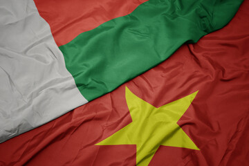 waving colorful flag of vietnam and national flag of madagascar.