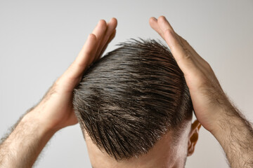 Hair loss problems. Man holding his head with hands. Styling hair at home.