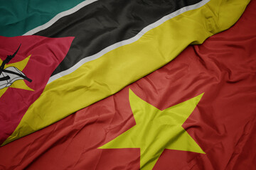 waving colorful flag of vietnam and national flag of mozambique.