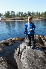 Fototapeta na wymiar Boy posing on stone island in Ladoga skerries