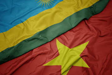 waving colorful flag of vietnam and national flag of rwanda.