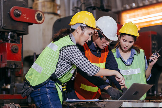 Asian Male Engineer Or Foreman Worker Training Female Trainee Using Program Or System In Industry Manufacturing Factory. Teamwork And Corporate People Working Hard In Industrial Construction Site