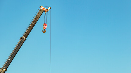 boom of a tower crane on a blue sky background, minimalism