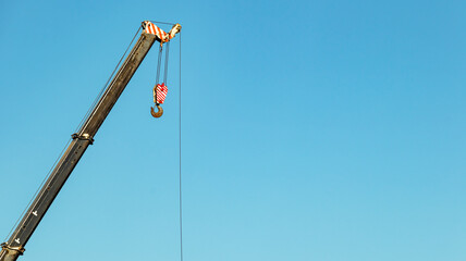Fototapeta premium boom of a tower crane on a blue sky background, minimalism