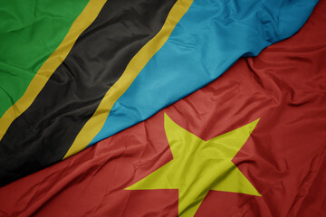 waving colorful flag of vietnam and national flag of tanzania.