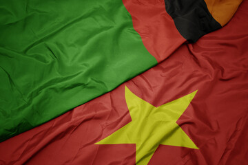 waving colorful flag of vietnam and national flag of zambia.