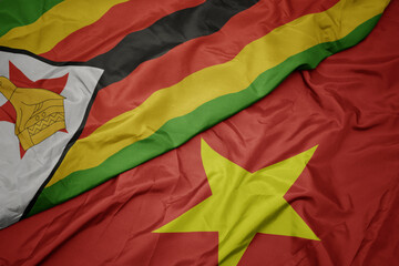 waving colorful flag of vietnam and national flag of zimbabwe.