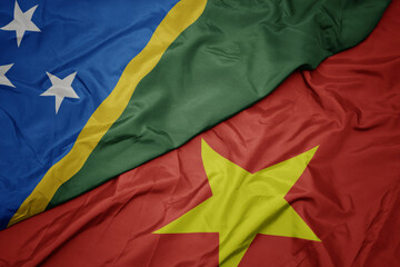 waving colorful flag of vietnam and national flag of Solomon Islands .