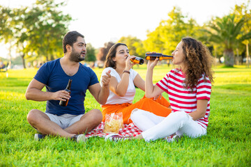 Three friends sitting on the grass in the park