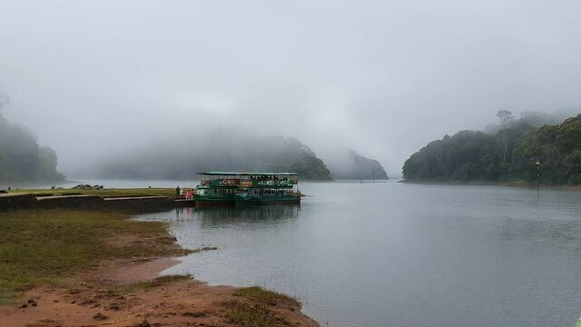 Boat safari in misty lake or foggy river on a winter morning in the wild forest or jungle. Video taken from boat. Indian wildlife. National Park wildlife sanctuary in Thekkady Kerala India.