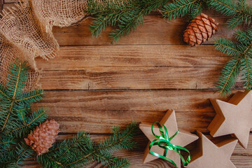 Christmas Flat lay of fir branches, cones, craft boxes in the star shape and burlap on a wooden background. Copy space