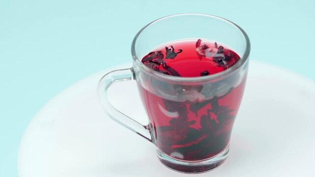 Cup of hibiscus tea spinning around isolated on blue