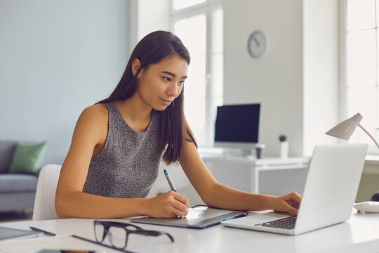 Young woman working on graphic design project using modern tablet and laptop computer