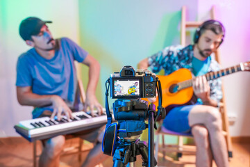 Handsome musicians working at home with his video camera making online concert. Working from home....