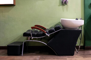 Armchair with ceramic shampoo basin fixture in barbershop