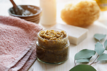 spa cosmetic products, milk soap, handmade sugar coffee scrub with coconut oil in glass jar and towel on wooden table