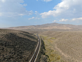 Aerial view of scenic road in the middle of green desert valley in Mono County, California, United States of America. 
